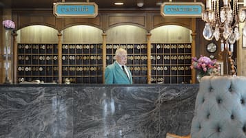A reception desk with a man standing behind it, a cash register, and a concierge sign.