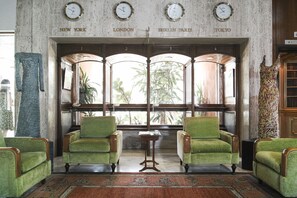 A lobby with four green armchairs, a wooden table, and a large window with views of plants. - Al Bustan Hotel & Spa (Beit Mery)