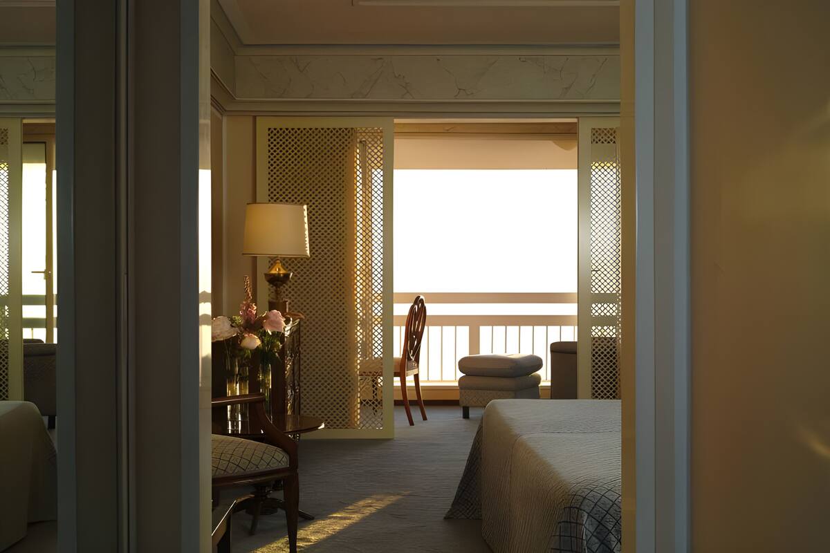 Une chambre d’hôtel avec un lit, une chaise, une table avec une lampe et une vue sur l’extérieur.
