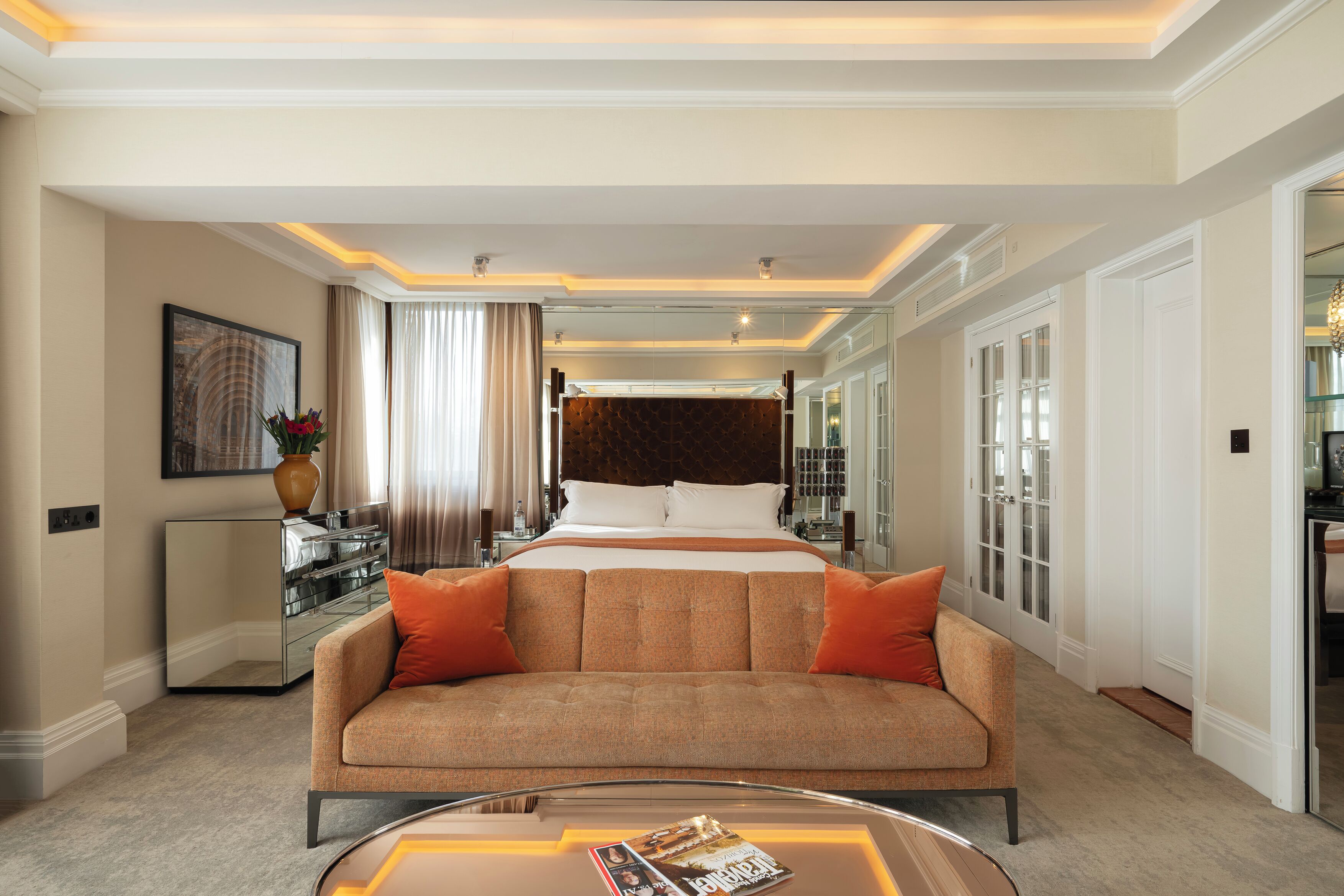 Ein Hotelzimmer mit einem großen Bett, einer Couch, einem Couchtisch und einem Spiegel.