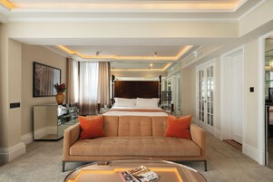 A hotel room with a large bed, a sofa, a coffee table, and a mirror.