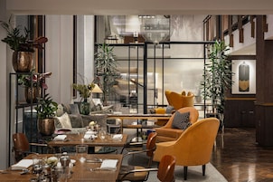A modern dining area with a wooden table, chairs, and potted plants.