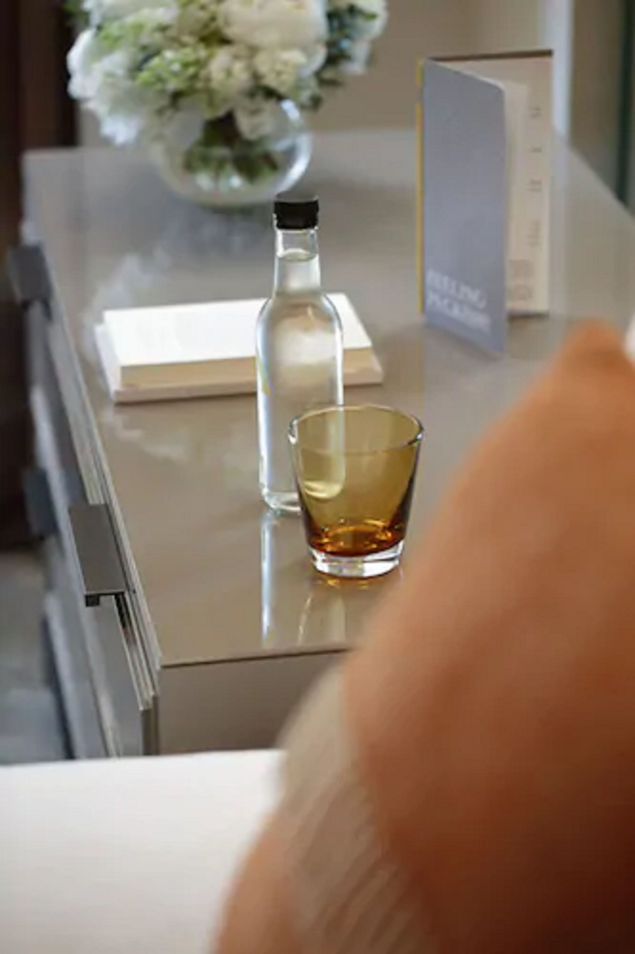 Zona de bar con una botella de licor, un vaso y un atril para el menú.