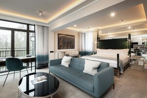 Una habitación de hotel moderna con una cama grande, un sofá, un escritorio y vistas al exterior.