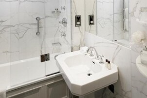 A bathroom with a white sink, a mirror, and a shower area.