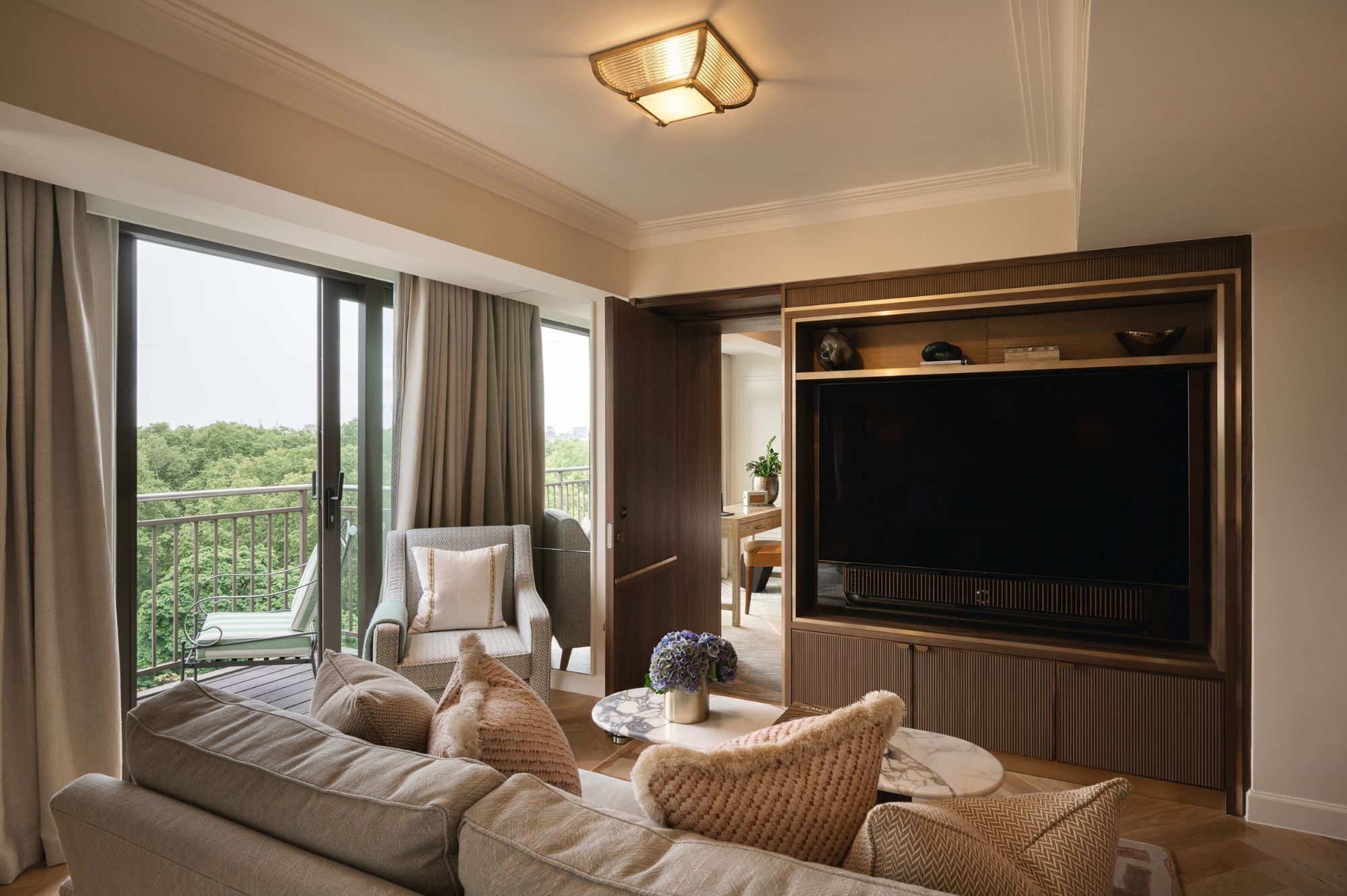 Ein modernes Wohnzimmer mit einer Couch, einem Fernseher und Blick auf einen Balkon.