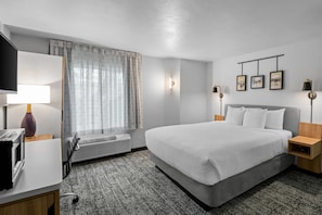 A hotel room with a bed, bedside tables, a desk, a lamp, a TV, a window with curtains, and wall-mounted picture frames. - Sleep Inn near Washington State Line (Post Falls)