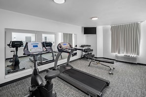 A hotel room with a treadmill, stationary bike, and dumbbells. - Sleep Inn near Washington State Line (Post Falls)