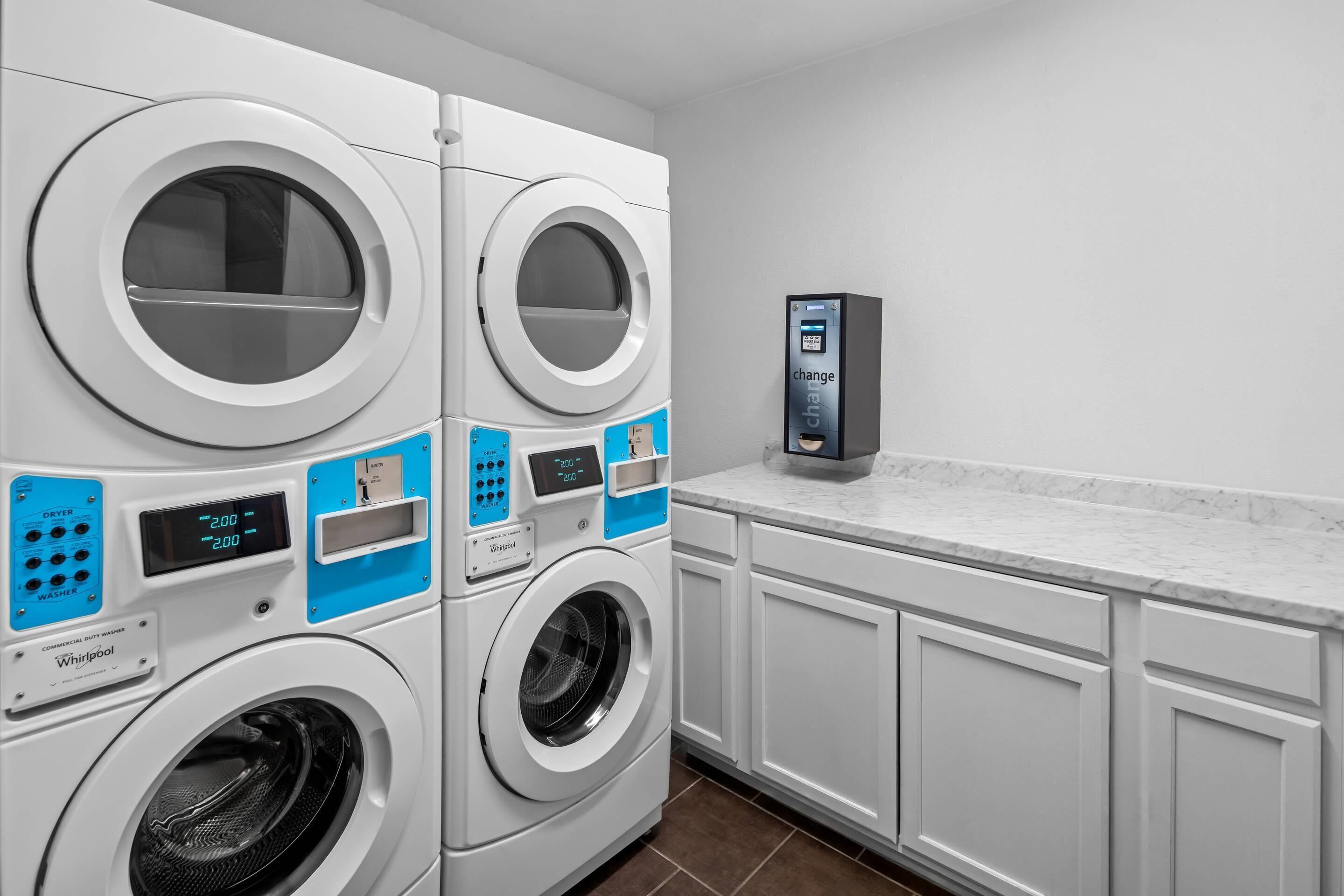 A laundry area with stacked washers and dryers, a digital control panel, and white cabinetry.