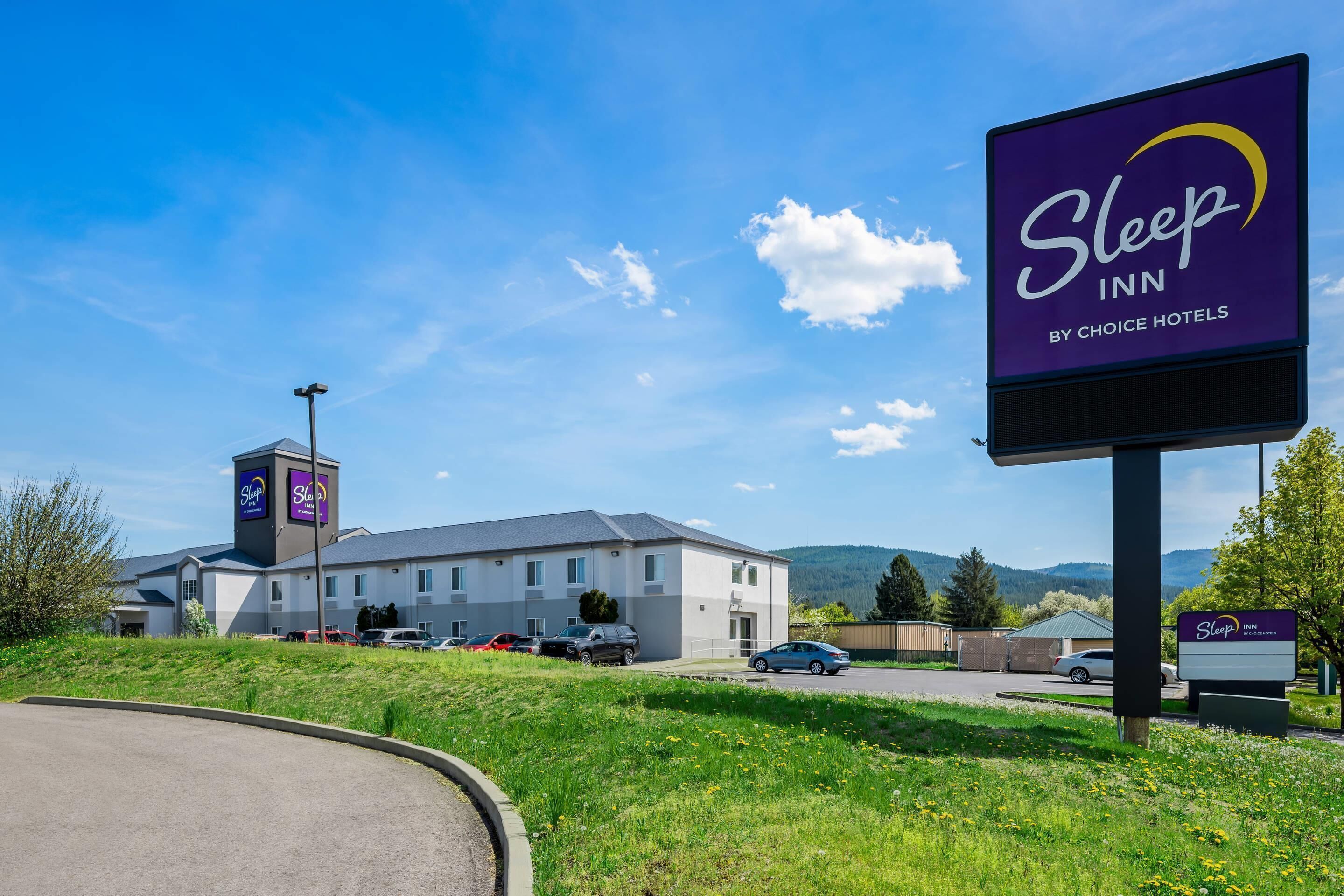 A Sleep Inn by Choice Hotels with a large sign, a parking lot, and a building with a flat roof.