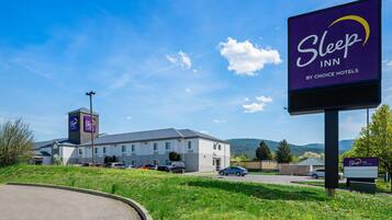 A Sleep Inn by Choice Hotels with a large sign, a parking lot, and a building with a flat roof.
