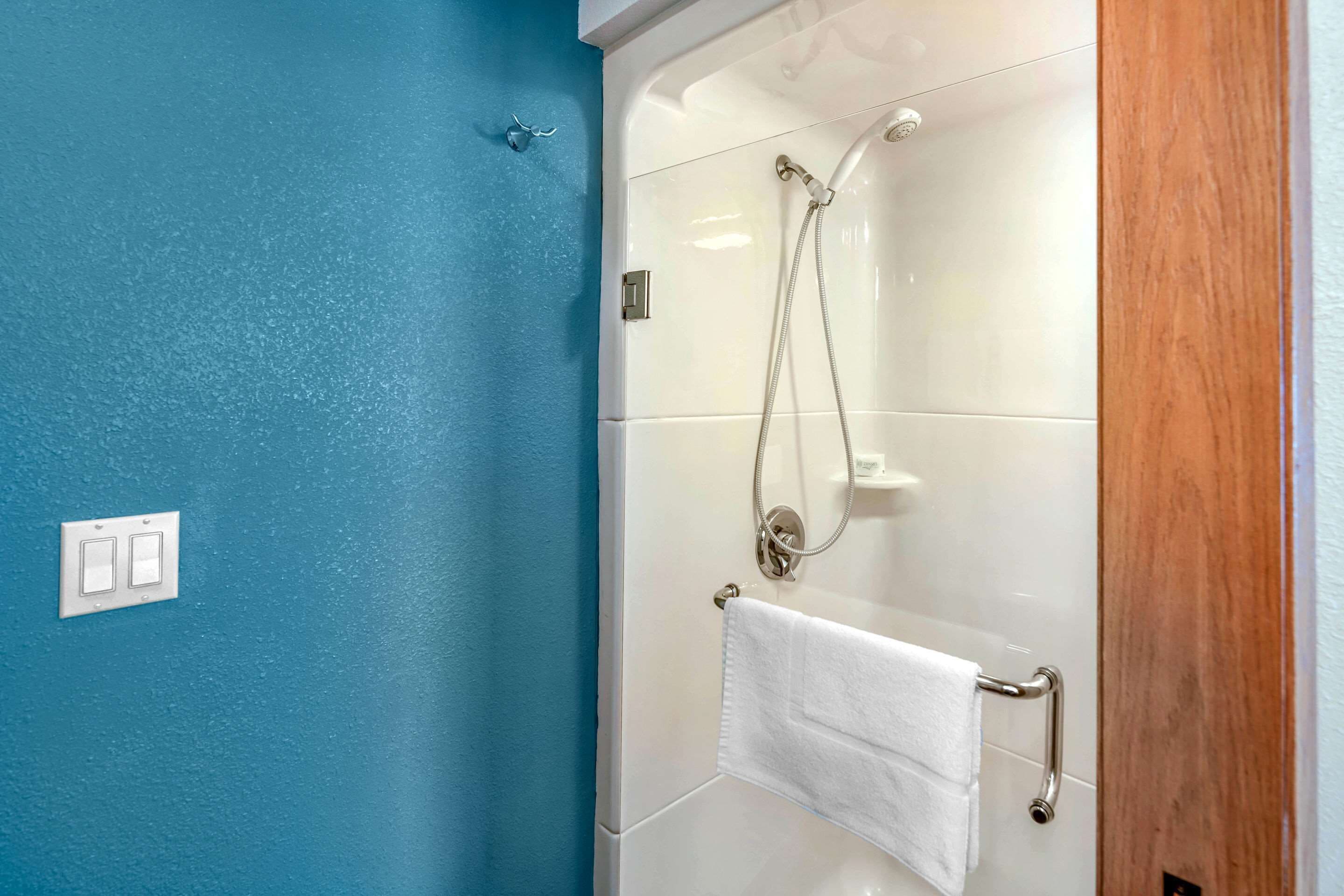 A bathroom with a glass shower enclosure, a white towel rack, and a blue wall.