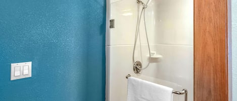 Une salle de bain avec une douche à parois de verre, un porte-serviettes blanc et un mur bleu.