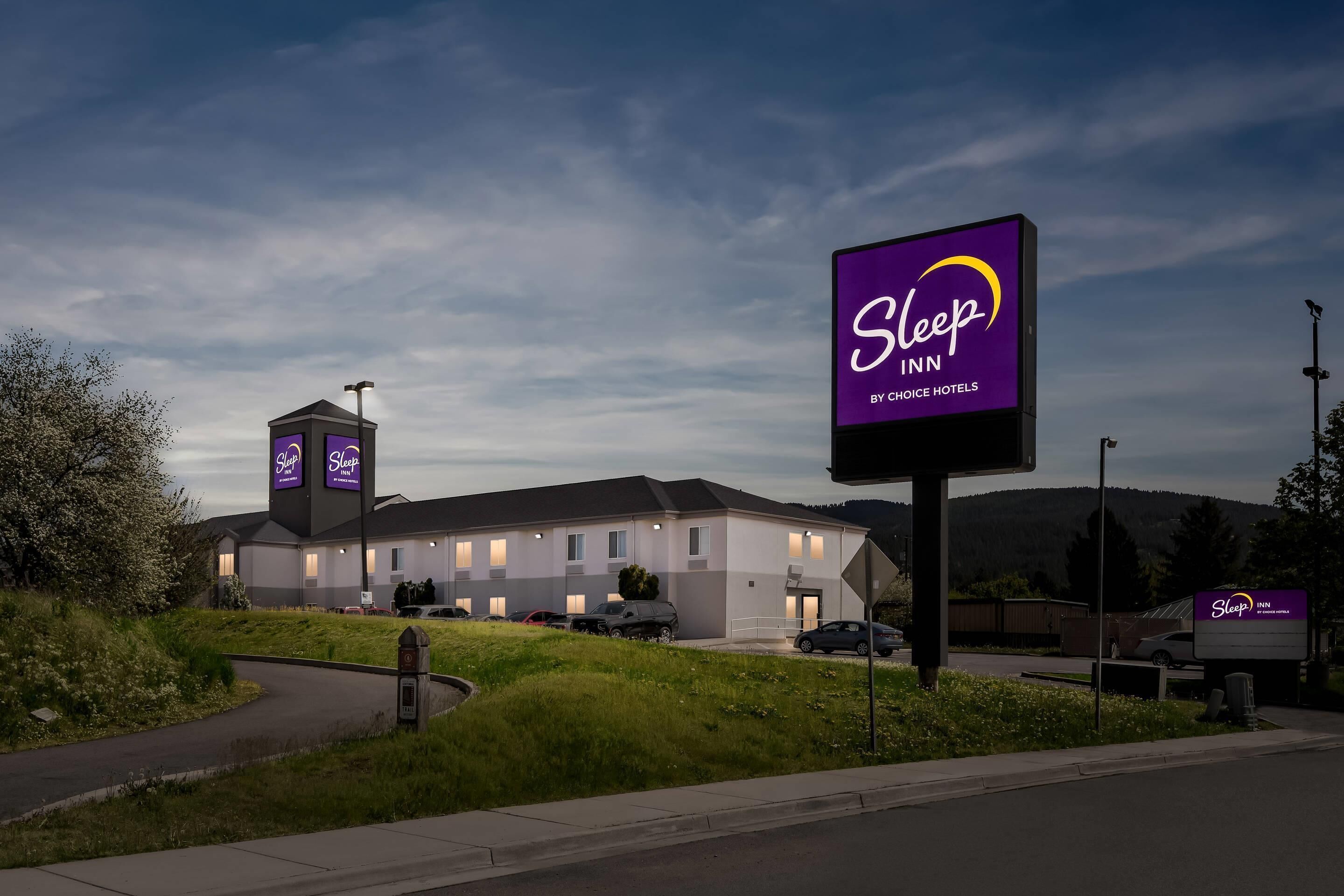 A Sleep Inn hotel with a modern design, a parking lot, and a grassy area in front.
