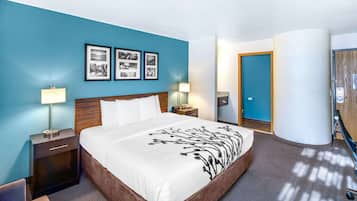 Habitación de hotel con una cama grande, dos mesitas de noche con lámparas, un cabecero de madera y una pared azul con detalles decorativos y cuadros enmarcados.