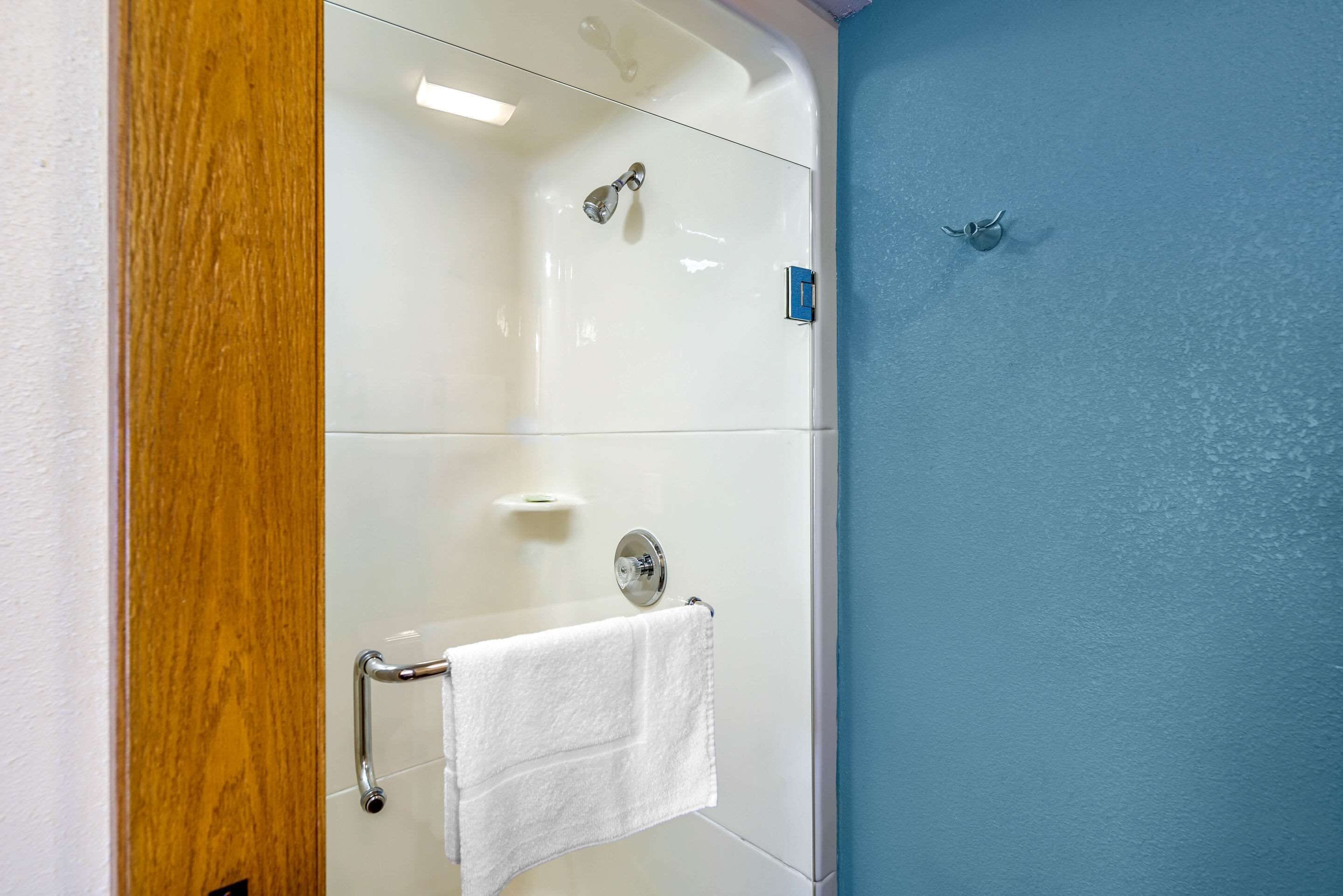 A bathroom with a glass shower enclosure, a white towel hanging on a rack, and a blue wall.