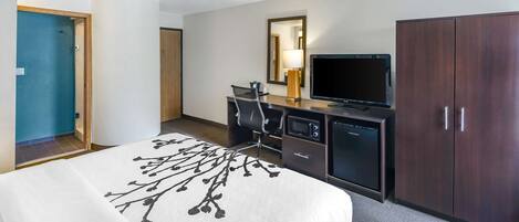 A hotel room with a bed, a desk with a computer, a television, and a wardrobe.