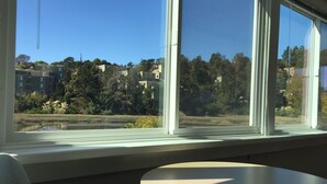 A room with a round table and a window overlooking a residential area with buildings and trees.