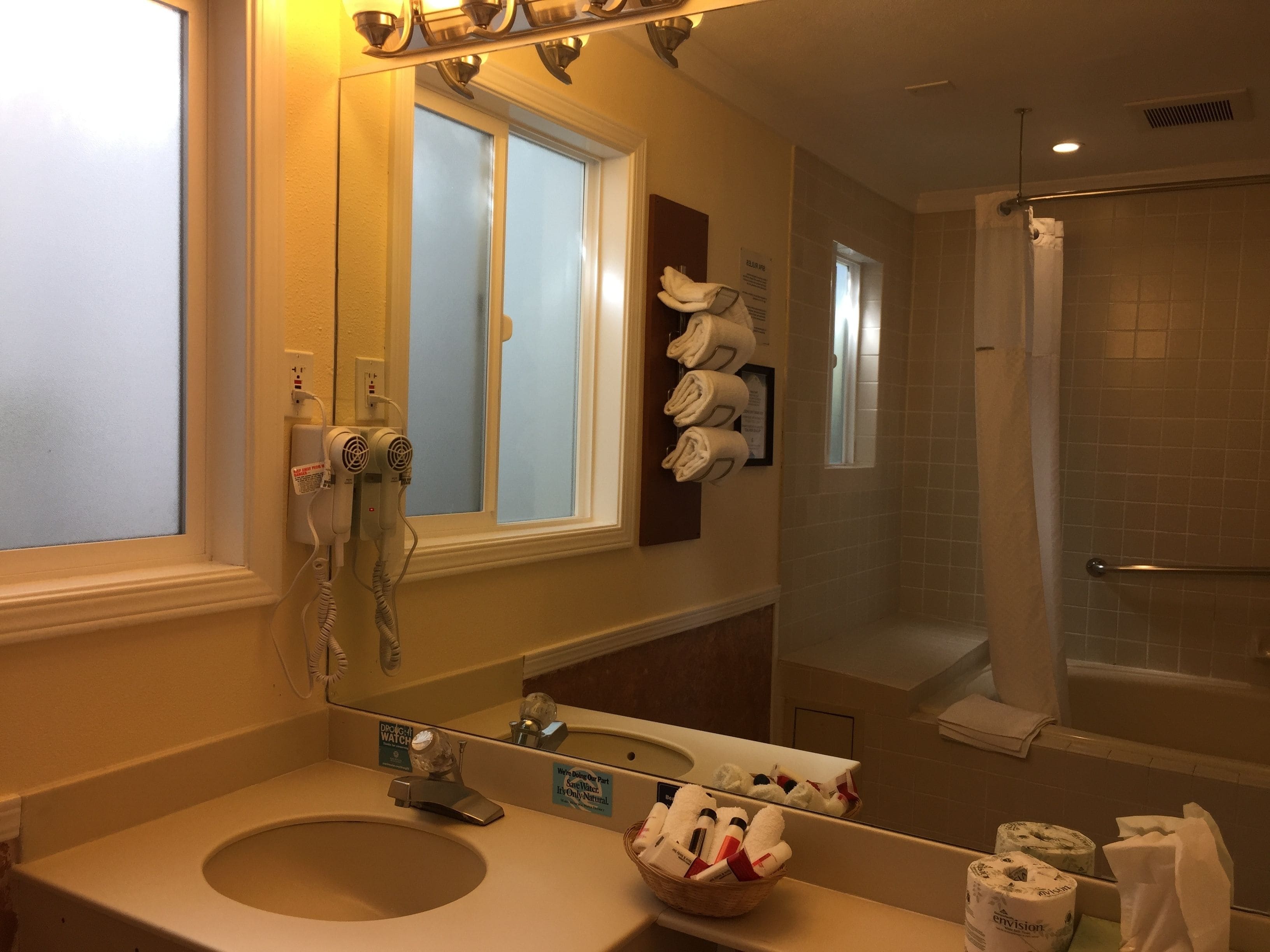 A bathroom with a sink, mirror, towel rack, and a shower area.