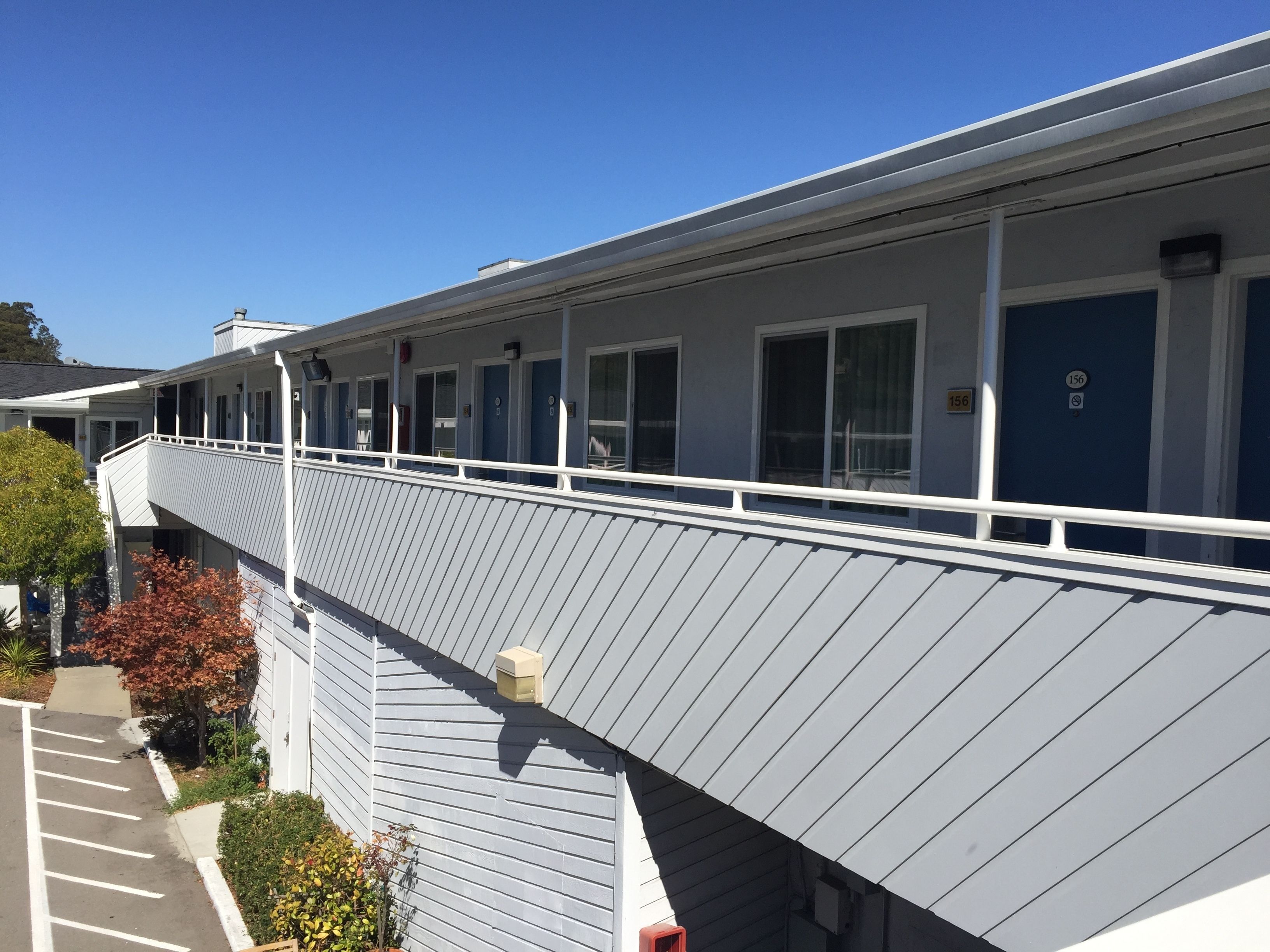 A motel with a covered walkway, multiple rooms, and a parking area.