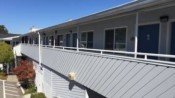 A motel with a covered walkway, multiple rooms, and a parking area.