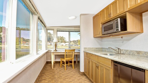 A kitchen with wooden cabinets, a built-in microwave, a sink, and a window overlooking a landscape.