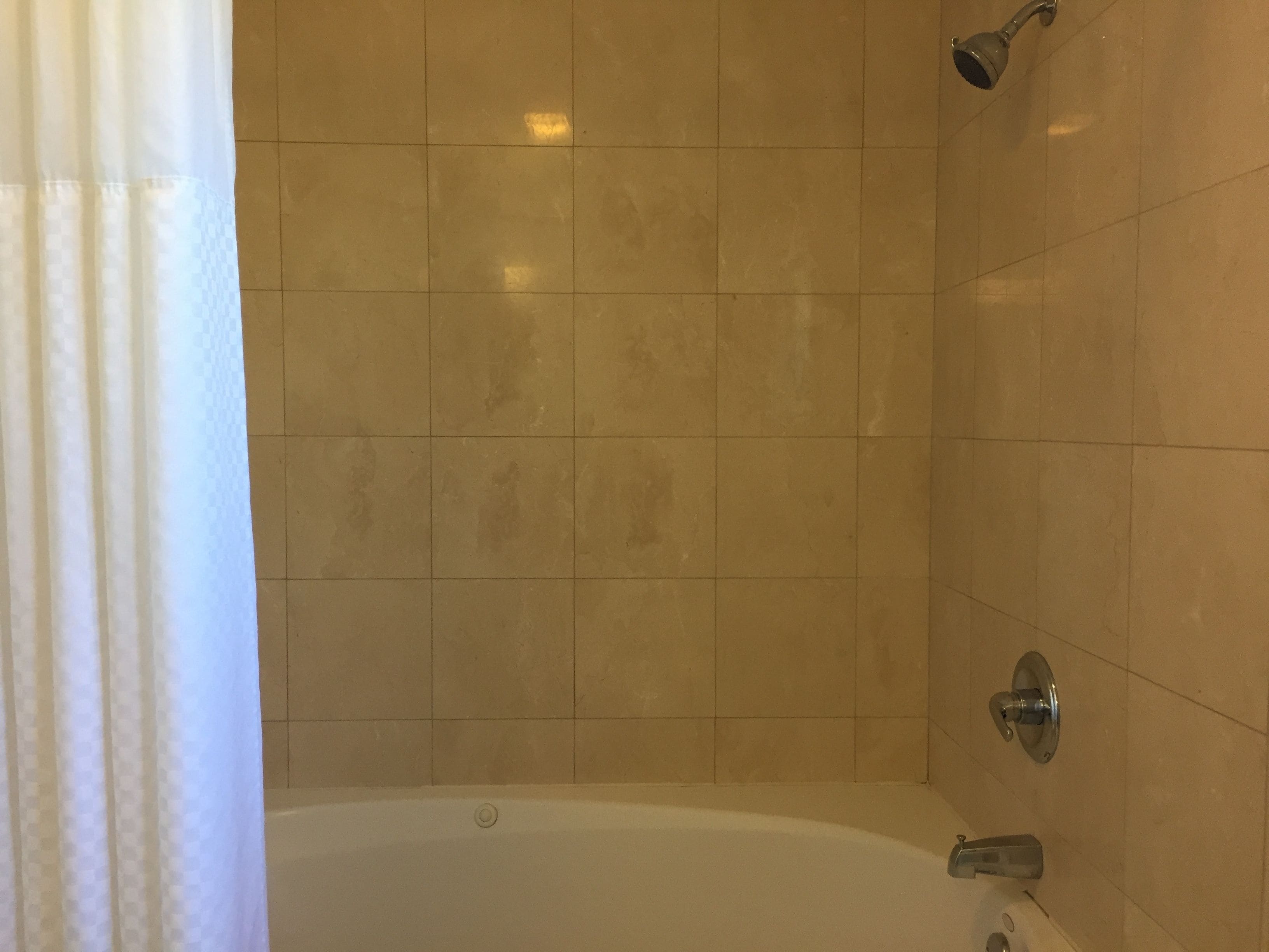 A bathroom with a bathtub, tiled walls, and a showerhead.
