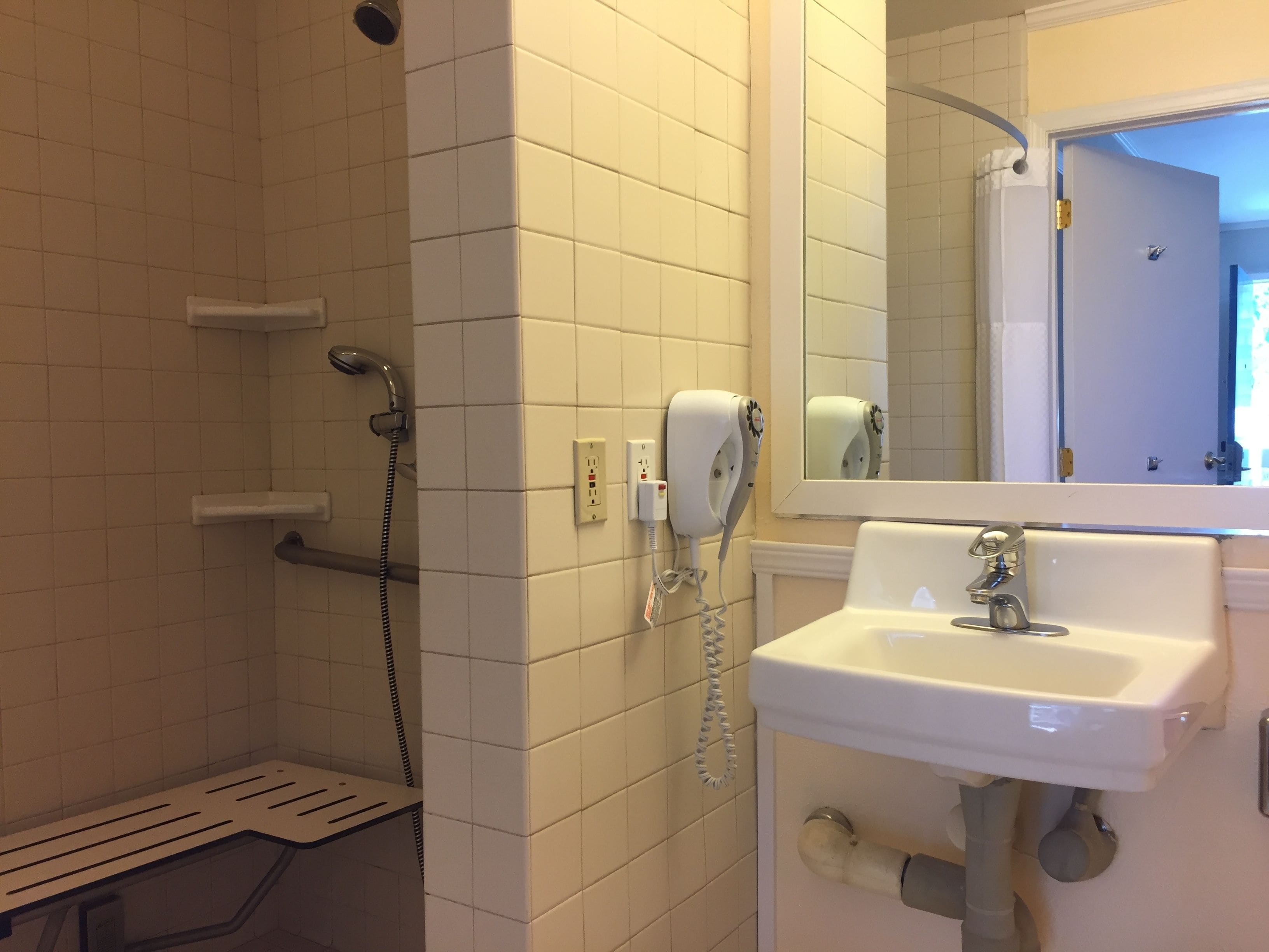 Une salle de bain avec une douche, un lavabo et un miroir.