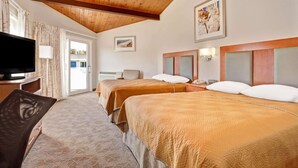 A hotel room with two beds, a TV, a desk, and a chair.