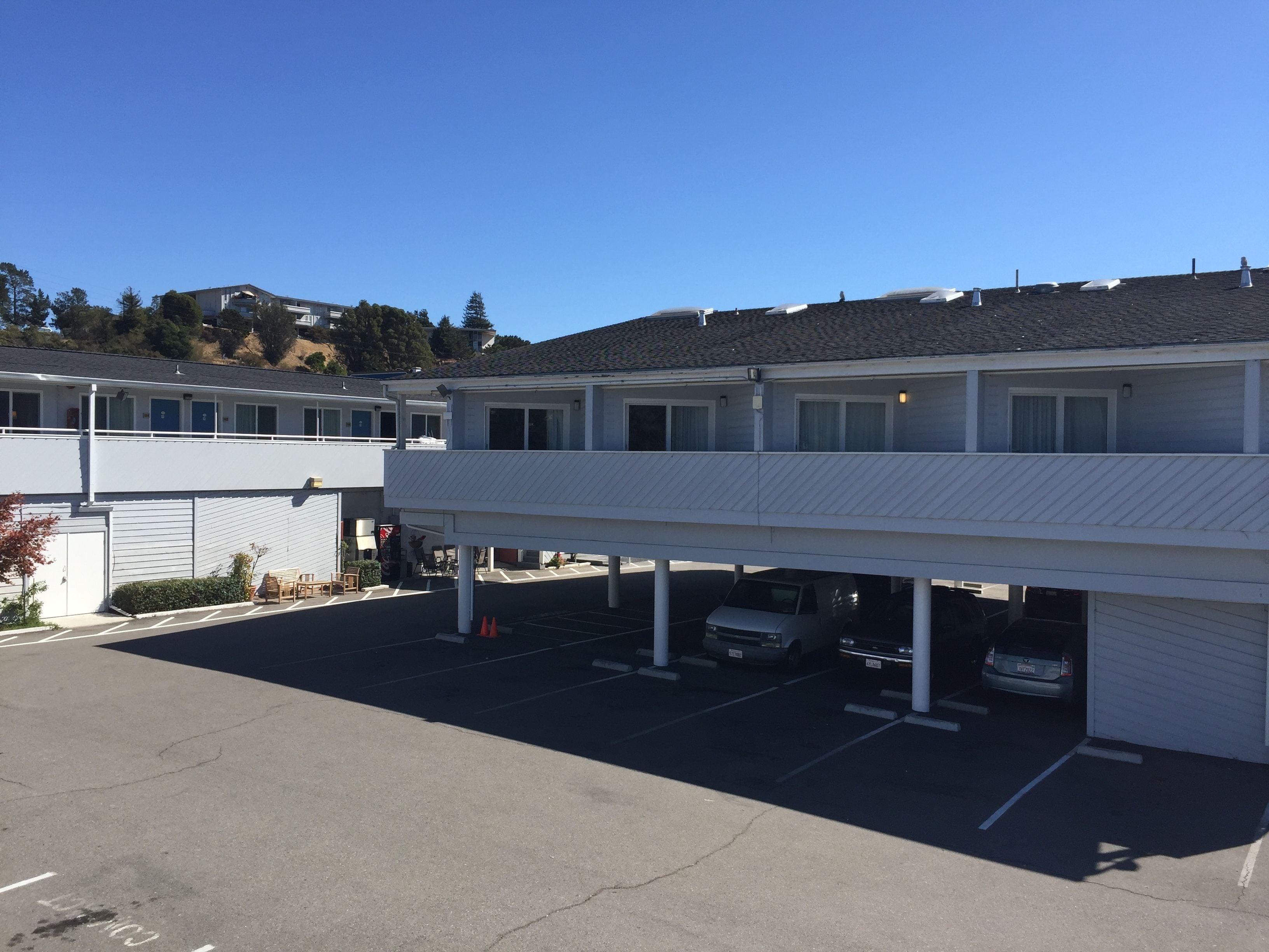 Un motel à plusieurs étages doté d’un parking et d’une zone de stationnement couverte.