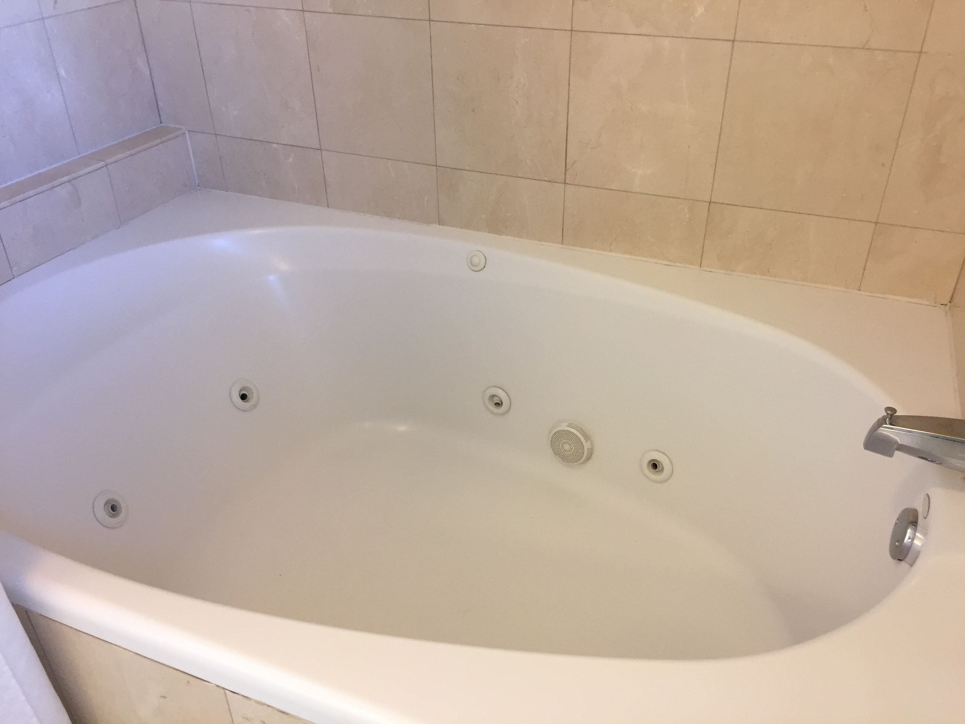 A white bathtub with four drain holes and a single faucet.