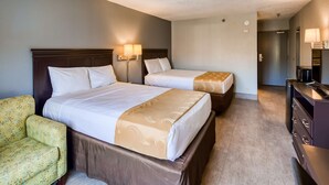 Ein Hotelzimmer mit zwei Betten, einer Schlafcouch, einem Schminktisch und einer Lampe.