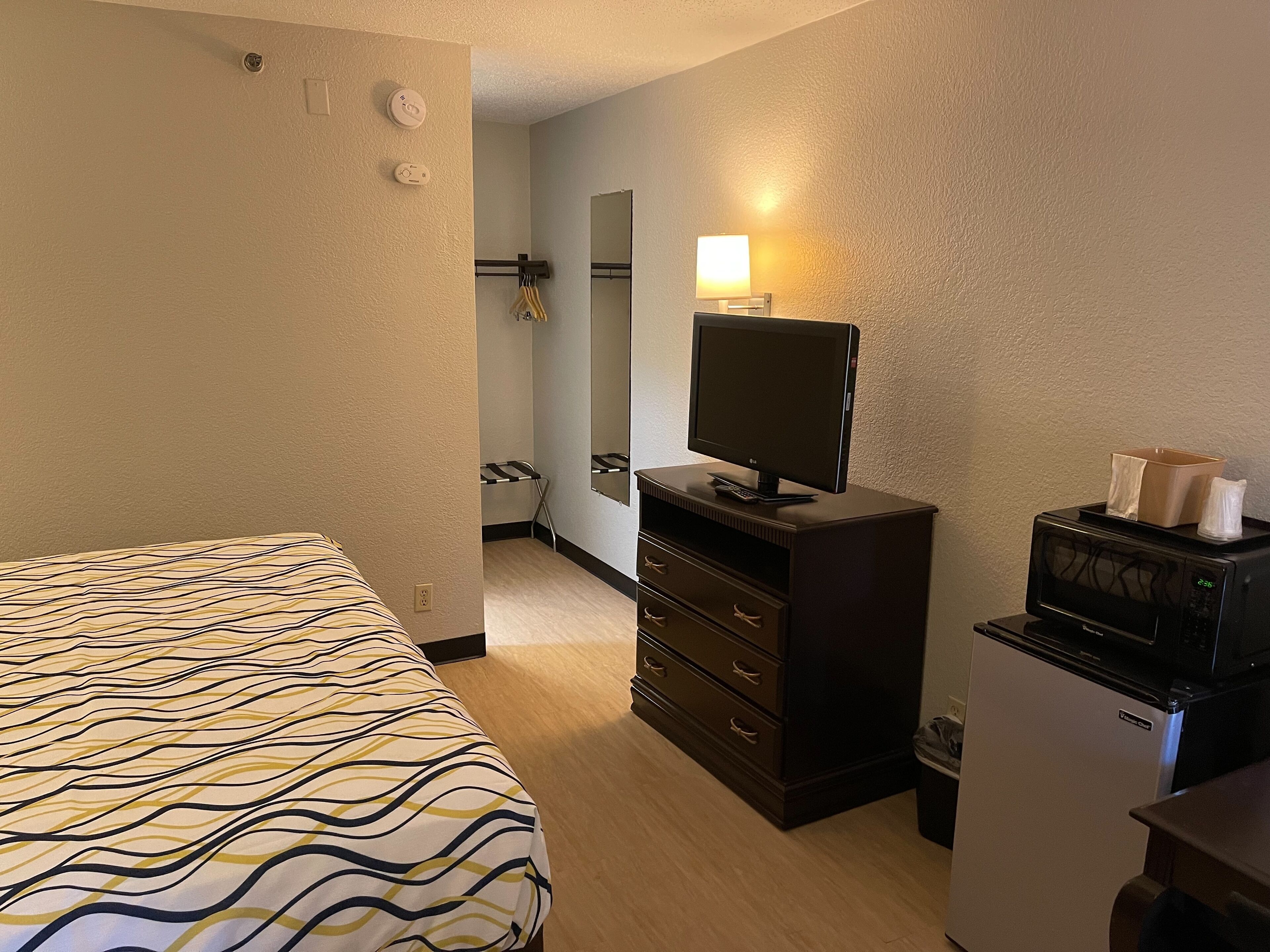 Habitació d'hotel amb llit, una petita còmoda, televisió, microones i nevera.