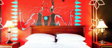Una habitación de hotel con una cama, dos mesitas de noche con lámparas, una pared con diseño rojo y negro y un cabecero de madera.