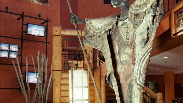 A lobby with a large sculpture, a wooden staircase, and a television screen. - Nativo Lodge Hotel Albuquerque (Albuquerque)