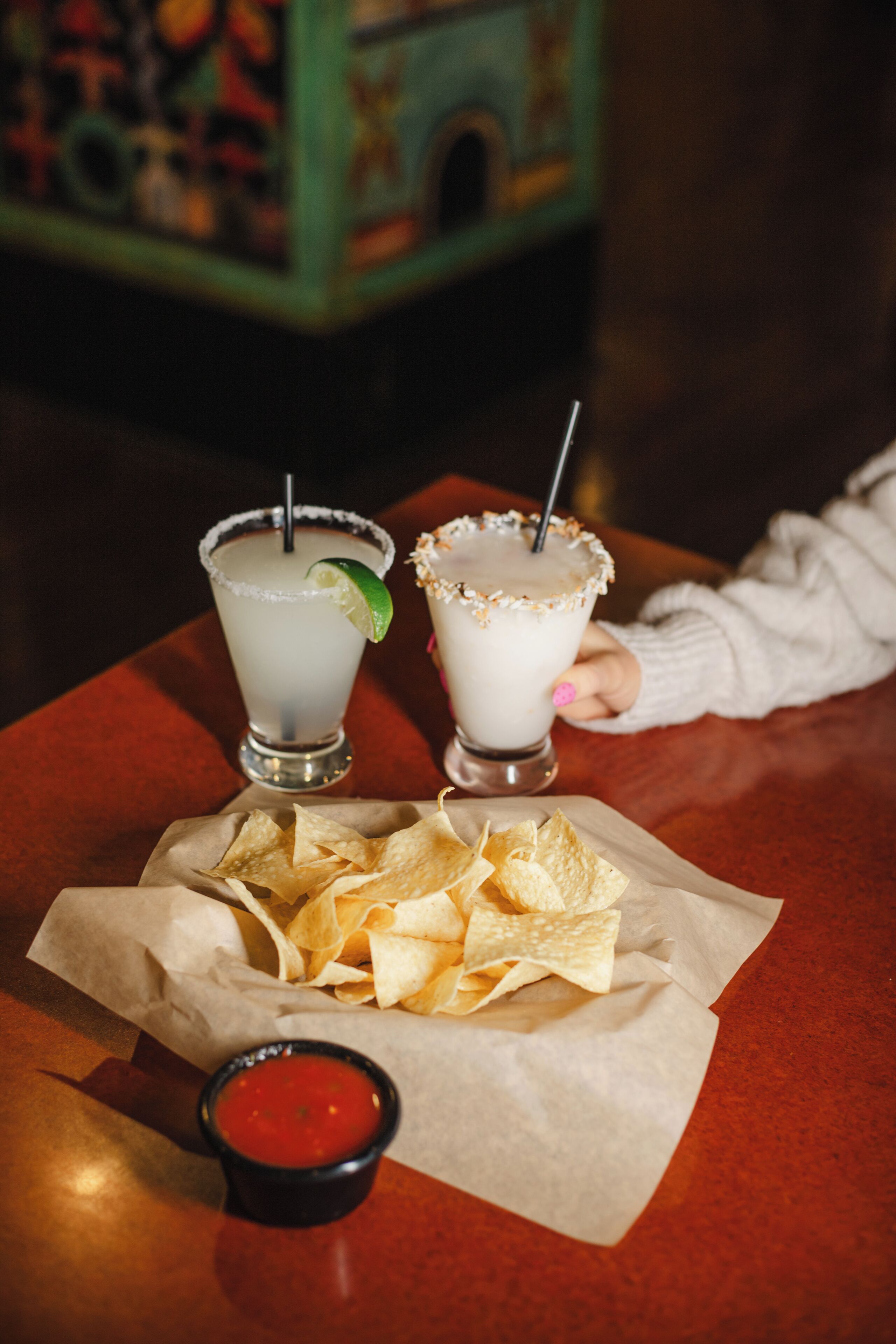 Zwei Margaritas auf einem Tisch mit Chips und Salsa.
