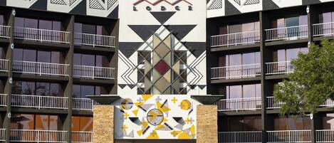 Un edificio de varios pisos con fachada geométrica, balcones y una entrada central con diseño decorativo.