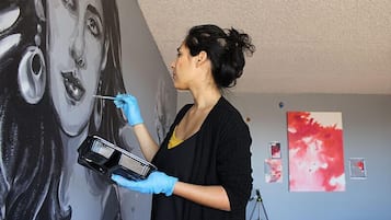 Une personne peignant un portrait sur un mur.