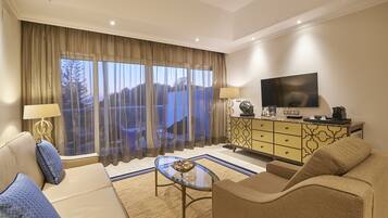 A modern living room with a sofa, a glass coffee table, a TV, and a large window with curtains.