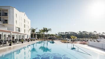 Una piscina al aire libre, sombrillas, sillones reclinables de piscina