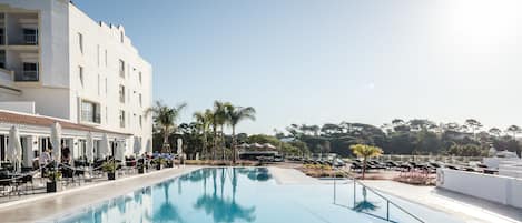 Una piscina al aire libre, sombrillas, tumbonas