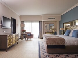 A hotel room with a bed, a desk, a chair, a TV, and a window with curtains.