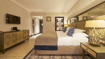 A hotel room with a large bed, a bedside table, a TV mounted on the wall, and a decorative headboard.