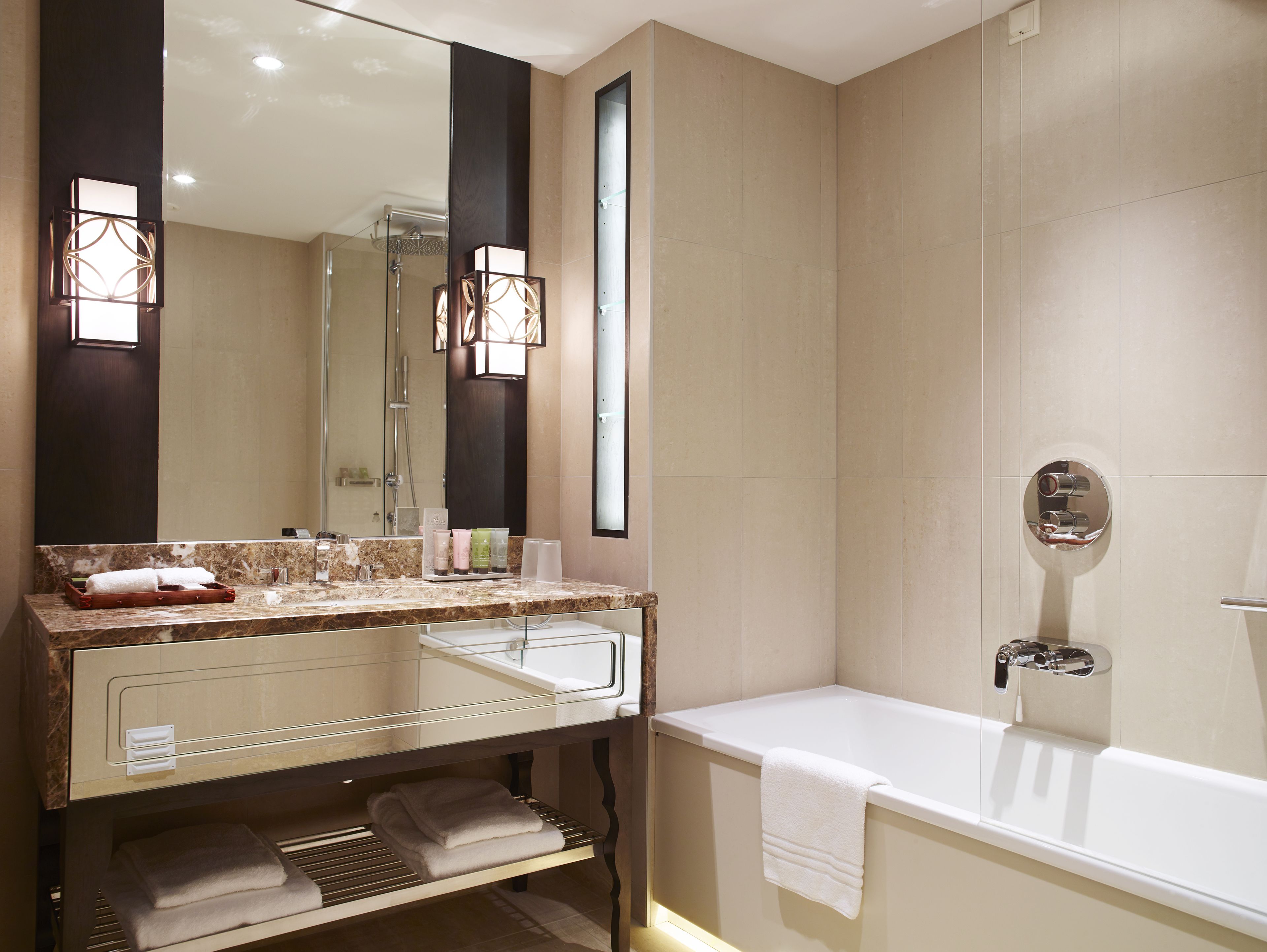 A modern bathroom with a large mirror, a bathtub, and a vanity with a sink.