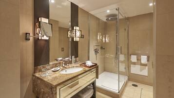 A modern bathroom with a glass-enclosed shower, a large mirror, and a marble vanity.