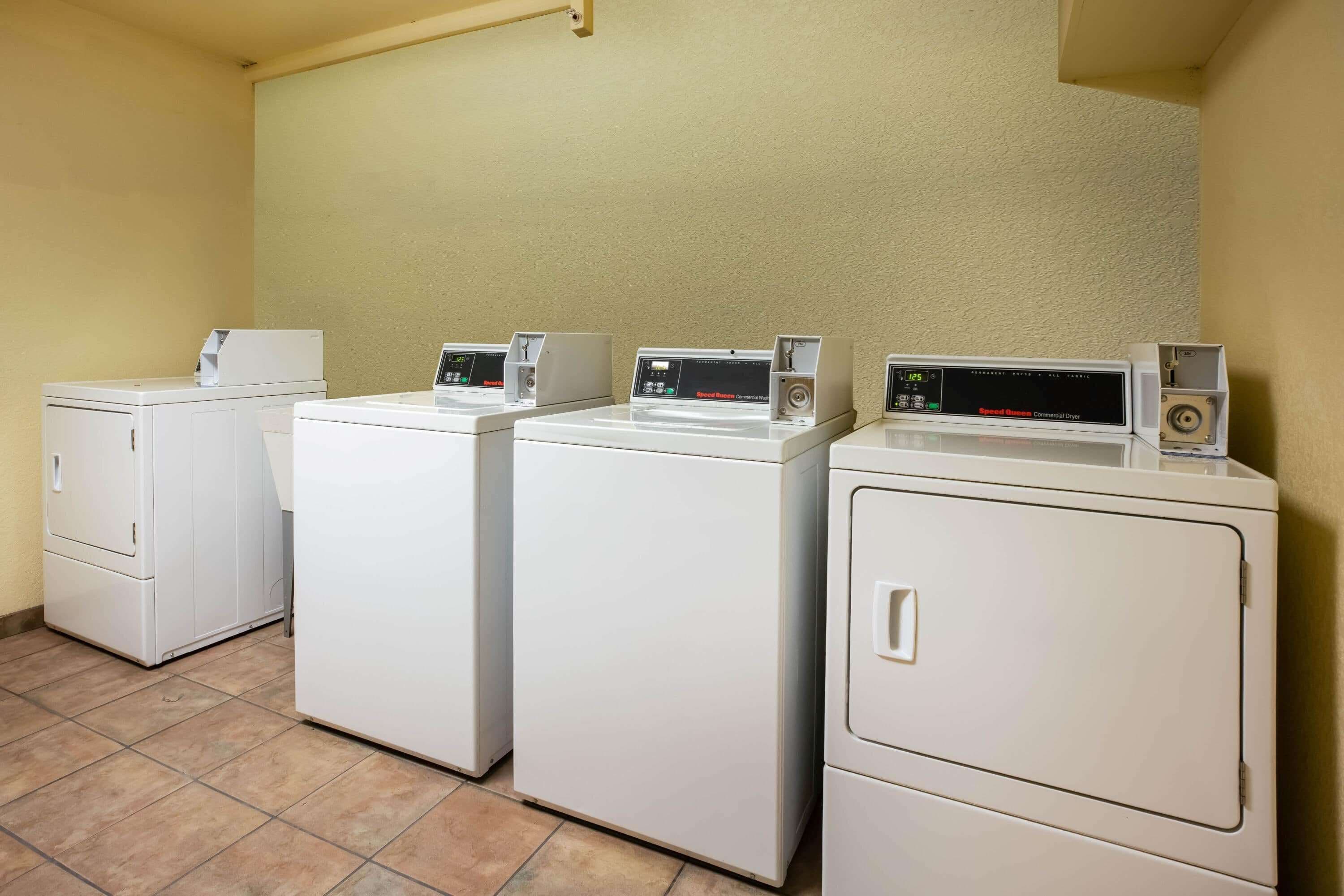A laundry area with three white washing machines and a dryer.