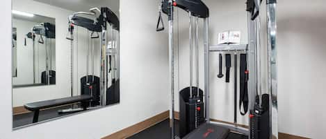 A gym with exercise equipment, a bench, and a mirror.