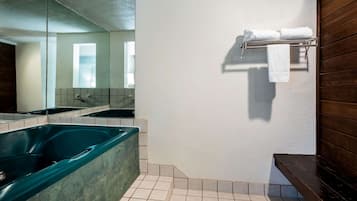 Un baño moderno con una bañera grande, un espejo y un perchero para toallas.