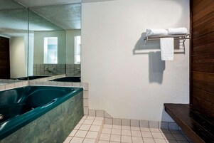 Un baño moderno con una bañera grande, un espejo y un perchero para toallas.