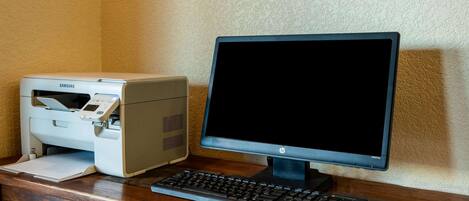 A desktop computer setup with a Samsung printer, HP monitor, Compaq keyboard, and mouse on a wooden desk.
